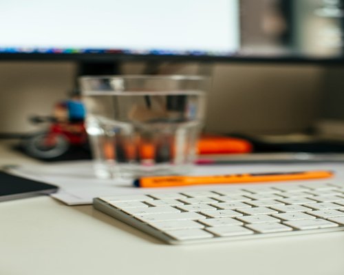 glass of water next to a workspace
